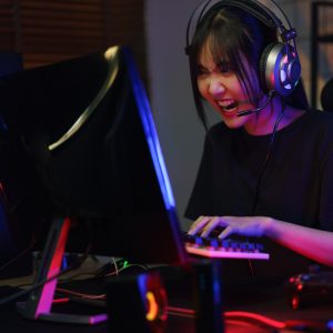 Female cyber hacker gamer serious face while pressing on keyboard to competition and playing games