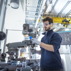 Robotics engineer fitting sensors to traditional engineering lathe in robotics research facility